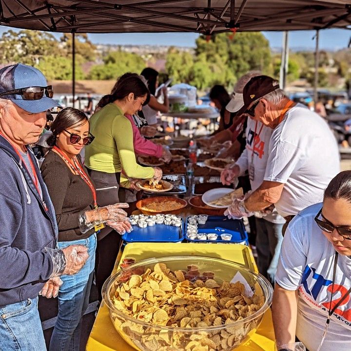 A group of people are standing around a table eating food.