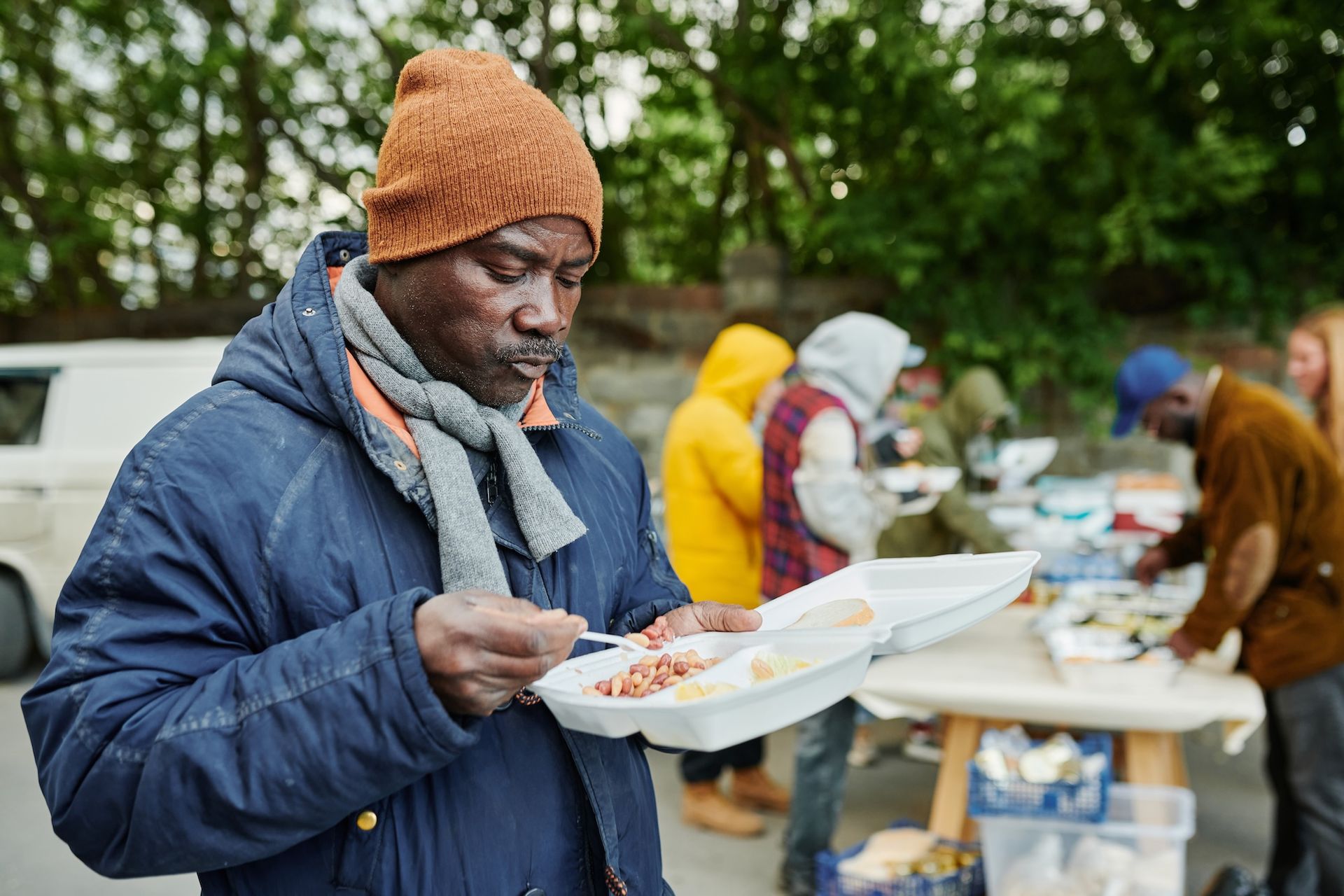 A man is eating food from a styrofoam container.